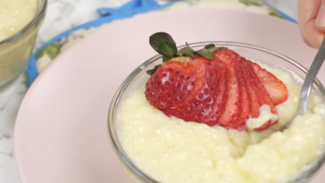 A close-up view of a bowl of homemade tapioca pudding with a single strawberry on top.